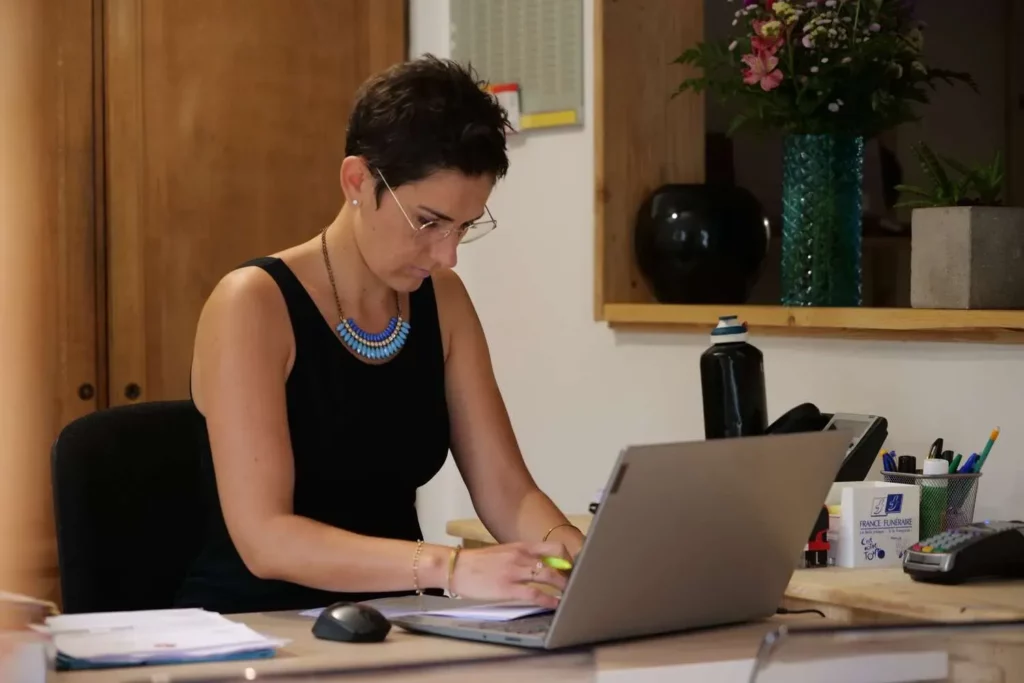 Assistante funéraire travaillant sur ordinateur dans son agence.