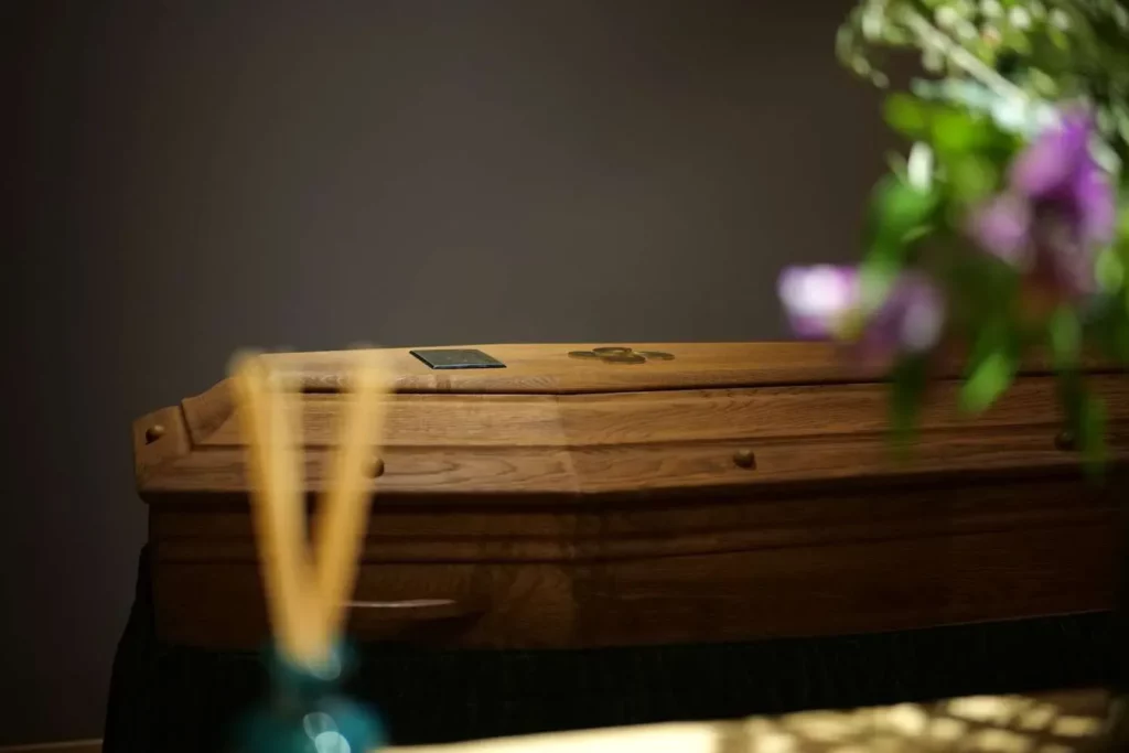 Cercueil en bois posé dans une chambre funéraire tamisée.