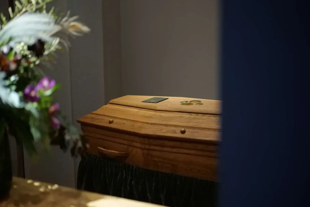 Cercueil en bois sous un éclairage doux dans un salon funéraire.
